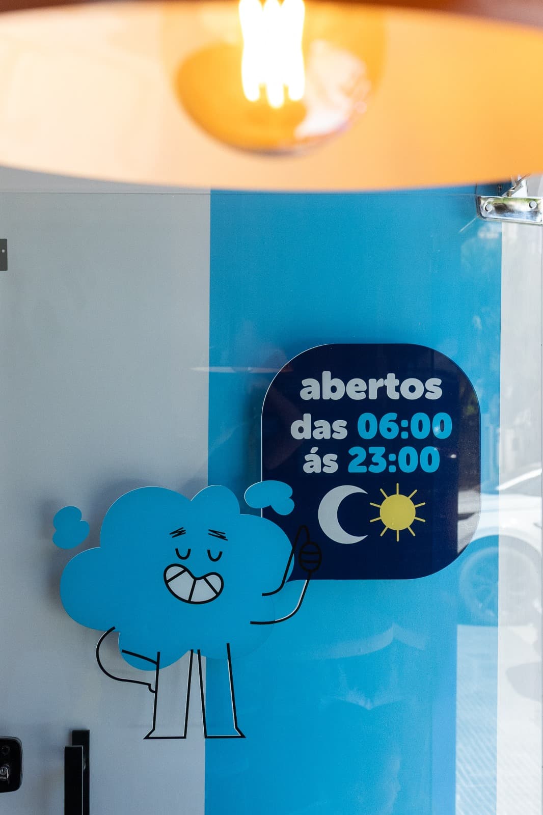 Adesivo na vitrine com mascote Espuma e horário 6h às 23h